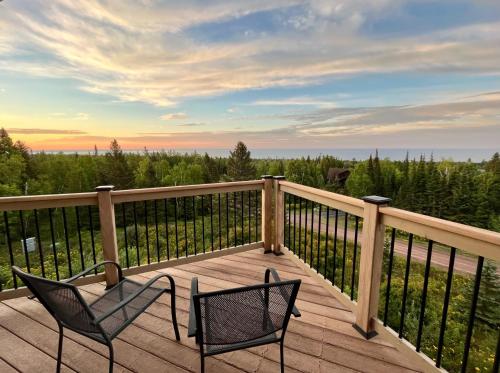 two chairs on a deck with a view of trees at MyLutsen in Lutsen