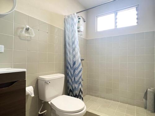 a bathroom with a toilet and a blue shower curtain at Cata Bed Breakfast Pet-friendly in San José