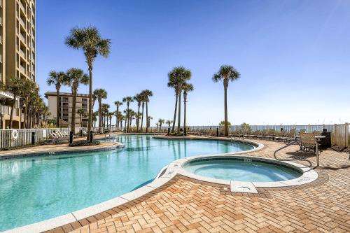 a large swimming pool with palm trees in a resort at Grand Panama by Panhandle Getaways in Panama City Beach