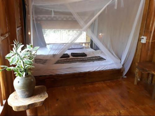 um quarto com uma cama de dossel e um vaso de plantas em Vu Linh Palm House Homestay - Bungalow em Yen Bai