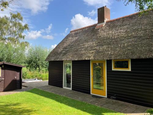 a black house with a thatched roof at Oasis holiday home in Giethoorn next to canal, boat extra in Giethoorn