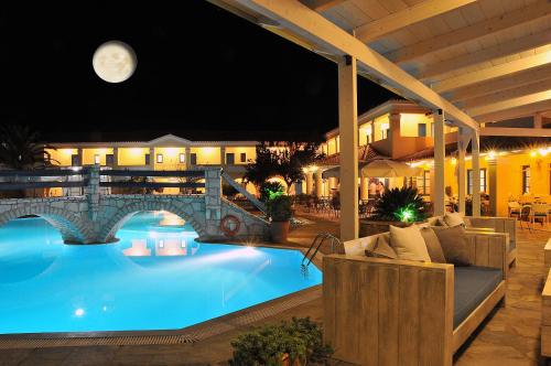 a pool at night with a full moon in the background at Karavostasi Beach Hotel in Perdika