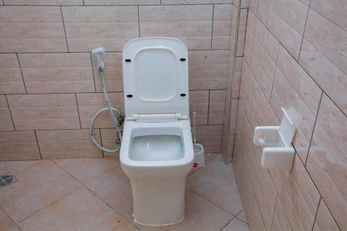 a bathroom with a toilet with the lid up at Mikoko Beach & Cottages in Bagamoyo
