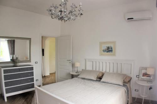 Habitación blanca con cama y lámpara de araña. en Villa Dei Sogni, en Greve in Chianti