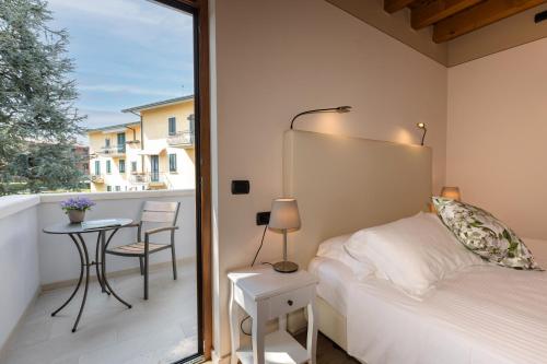 a bedroom with a bed and a balcony with a table at Charming Sirmione in Sirmione