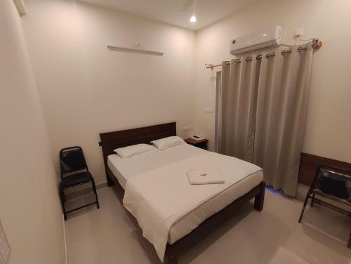 a small bedroom with a bed and a curtain at MITRA HOTELS in Mysore