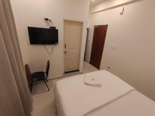een kamer met een bed en een tv aan de muur bij MITRA HOTELS in Mysore