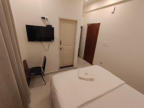 a room with a bed and a tv on the wall at MITRA Hotels & Retreat in Mysore