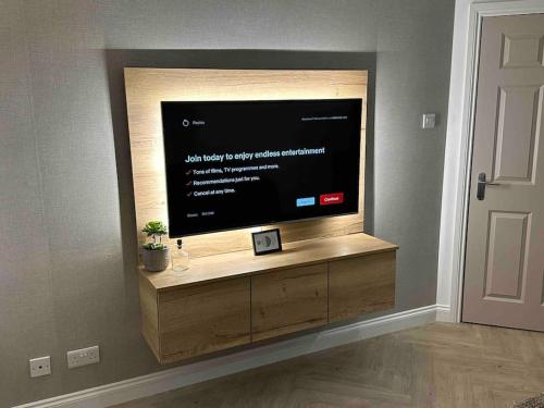 TV de pantalla plana en un centro de entretenimiento de madera en Premium executive Apartment in Dunfermline, en Dunfermline