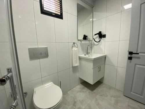 a white bathroom with a toilet and a sink at Eraliz in Buca