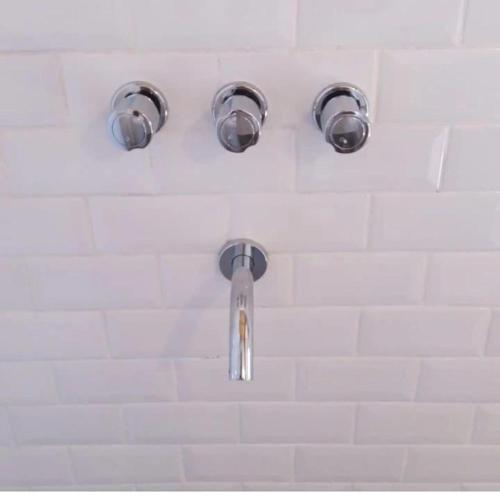 a shower with three lights on a white wall at A Morriña in Santa Lucía