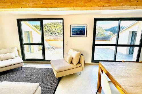 a living room with a couch and a chair and windows at Au pied du port, 150m2 - Parking gratuit, Climatisation, Terrasses - Standing in Bonifacio