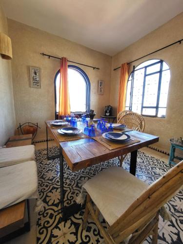 a dining room with a wooden table and chairs at Dar Janoub in Beni Balla