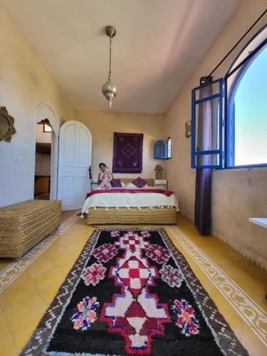 a child sitting on a bed in a bedroom at Dar Janoub in Beni Balla