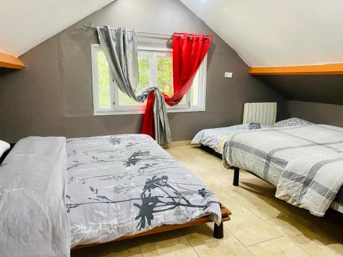 1 Schlafzimmer mit 2 Betten und einem Fenster mit roten Vorhängen in der Unterkunft Maison et sa dépendance ss voisinage dans les vergers de Montmorency in Saint-Brice-sous-Forêt