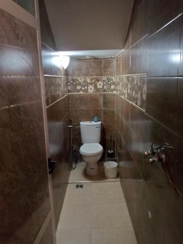 a bathroom with a toilet and a tiled wall at شقة فونتي العليا in Agadir
