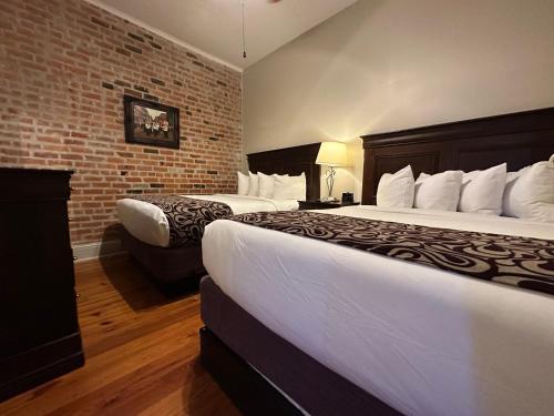 een hotelkamer met 2 bedden en een bakstenen muur bij Inn on St. Peter, a French Quarter Guest Houses Property in New Orleans