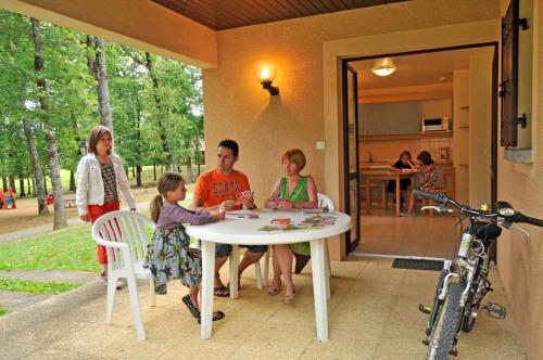 eine Gruppe von Menschen, die um einen weißen Tisch sitzen in der Unterkunft VVF Périgord Sorges-en-Périgord in Sorges