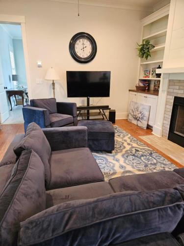a living room with a couch and a clock on the wall at Low Country Cottage in Beautiful Habersham in Beaufort
