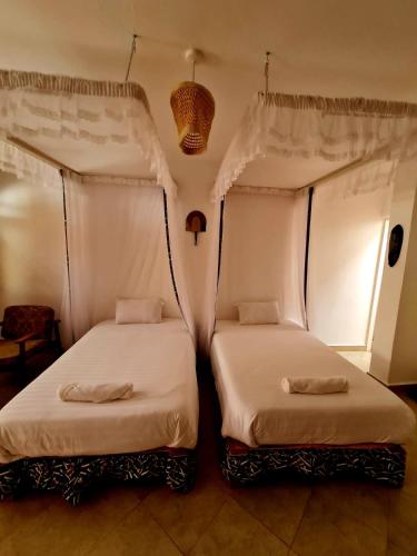 two beds sitting next to each other in a room at GKAT Resort in Mbarara