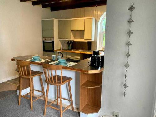 a kitchen with a counter with chairs and a table at Stunning Cottage in Kilmun Argyll - sleeps 2 in Dunoon
