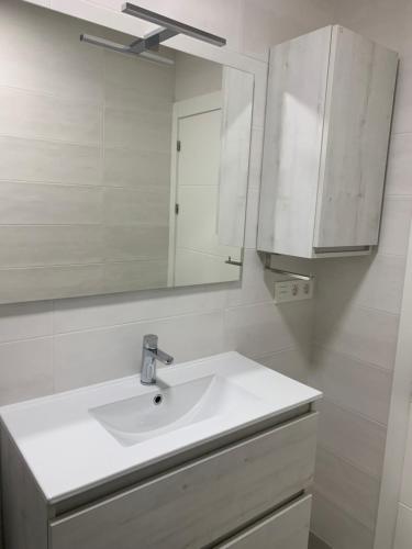 La salle de bains est pourvue d'un lavabo blanc et d'un miroir. dans l'établissement Coqueto apartamento en Gijon, à Gijón