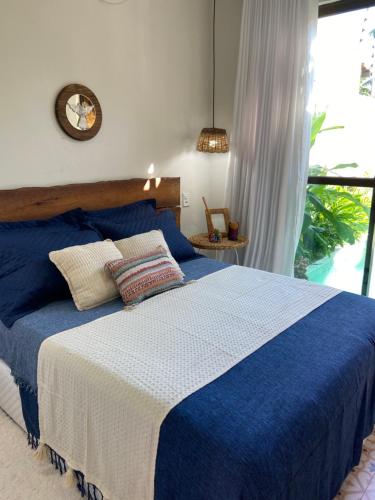 a bedroom with a blue and white bed with a window at Casa Prainha in Praia do Frances