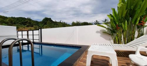 ein Swimmingpool mit zwei Stühlen und einem weißen Zaun in der Unterkunft Pool Villa Sattahip White House in Sattahip