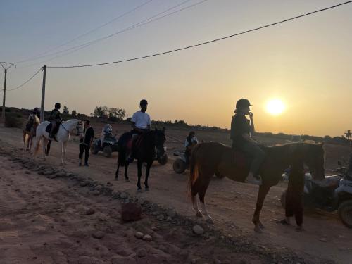 a group of people riding horses on a dirt road at Aghmat Lodge Guest house in Marrakech