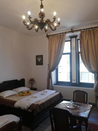 a bedroom with a bed and a table and a chandelier at Casa Continentelor in Cîmpulung
