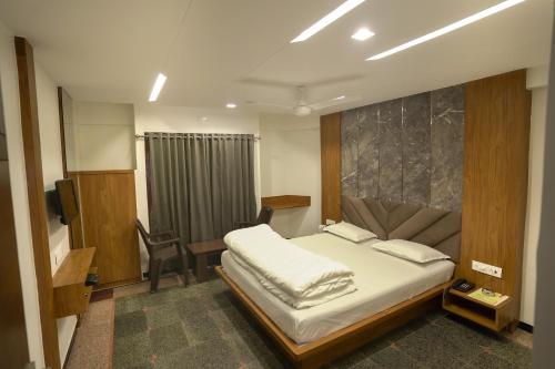 a bedroom with a bed and a desk and a chair at Hotel Shertown in Ahmedabad