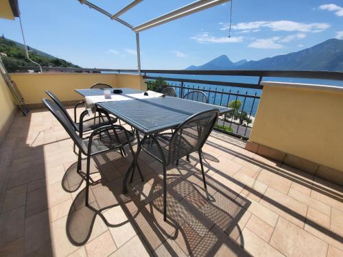 a table and chairs on a balcony with a view of the water at Penthouse CASA ALKEA Masse Lake view in Brenzone sul Garda