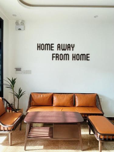 a couch in a room with a home away from home sign on a wall at Under the Sun Homestay in Hue
