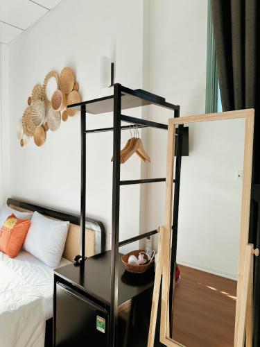 a black shelf next to a bed with a mirror at Under the Sun Homestay in Hue