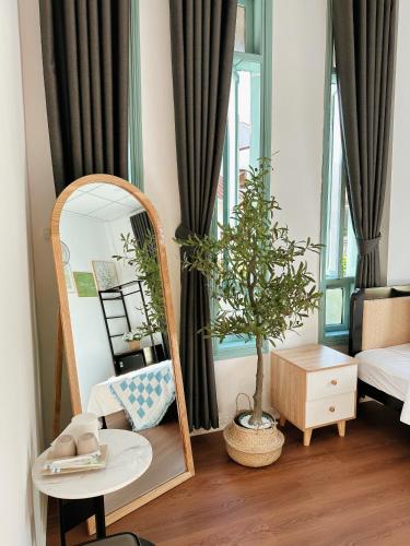 a mirror and a chair in a room with a tree at Under the Sun Homestay in Hue