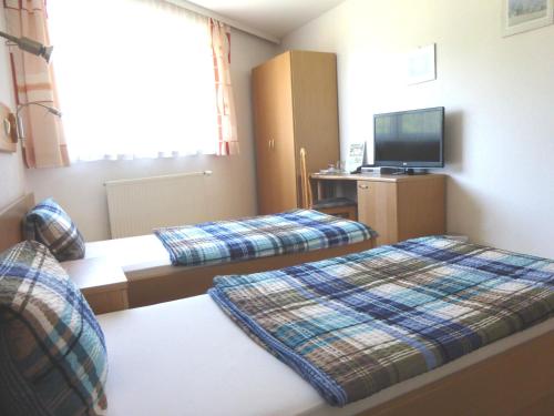a hotel room with two beds and a flat screen tv at Pension Feiken in Wesenufer
