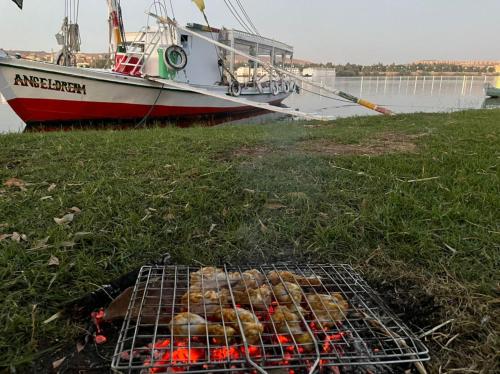 a grill with food on it next to a boat at Freedom Boat in Naj‘ al ‘Amrāb