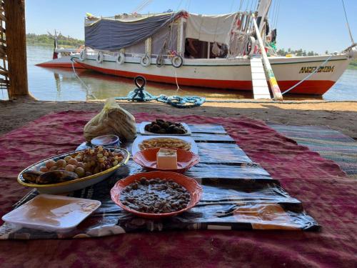 a table with bowls of food and a boat at Freedom Boat in Naj‘ al ‘Amrāb