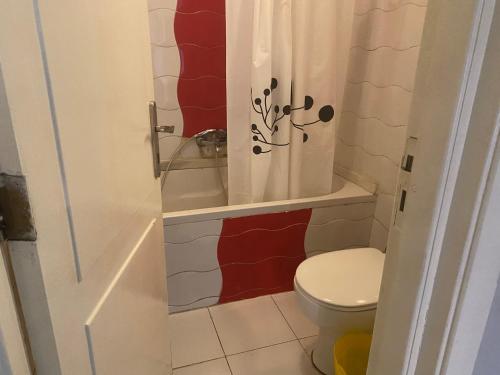 a bathroom with a toilet and a shower curtain at A cosy Apartment just for you to relax in 6th Of October