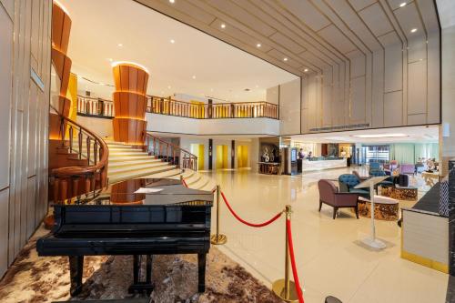 a grand staircase with a piano in a living room at Siam Mandarina Hotel - Free BKK Airport Shuttle in Lat Krabang