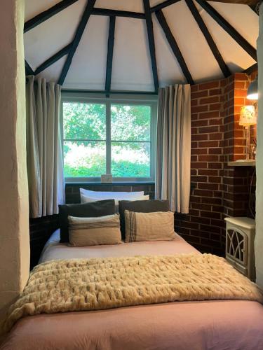 Cama grande en habitación con ventana en The Snug at Littledown, en Lewes