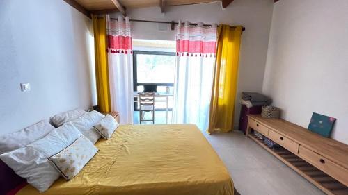 - une chambre avec un grand lit jaune et une fenêtre dans l'établissement Harena Villa, à Morondava
