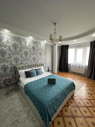 um quarto com uma cama grande e um cobertor azul em Просторная квартира в верхней части мегаполиса em Almaty