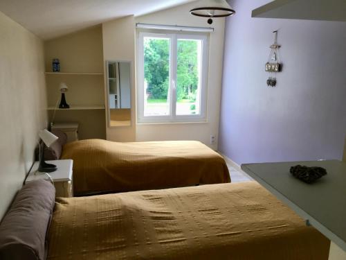 a room with two beds and a window at La Frouardière, 3 gîtes de charme in Antigny
