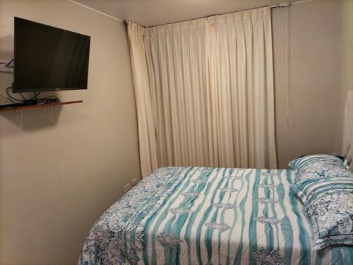 een slaapkamer met een bed en een flatscreen-tv bij Lugar cómodo y seguro in Lima