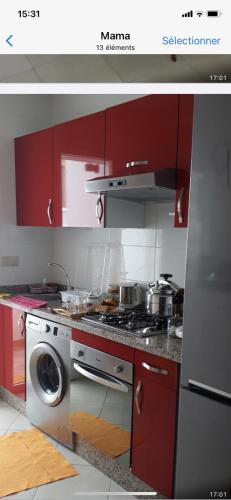 een keuken met rode kasten en een wasmachine bij Mbari in Martil