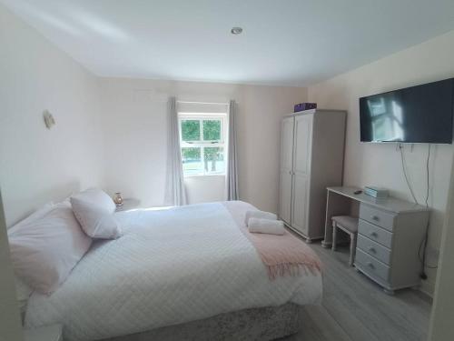 een slaapkamer met een bed, een dressoir en een televisie bij Kilarney cottage in Killarney