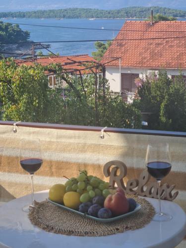een schaal fruit op een tafel met twee glazen wijn bij Bura in Jelsa