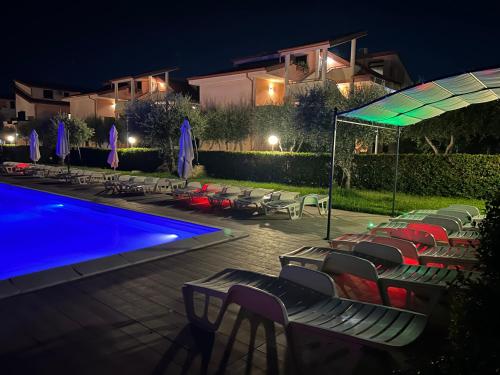 a swimming pool at night with chairs and umbrellas at Hotel Park in Rossano