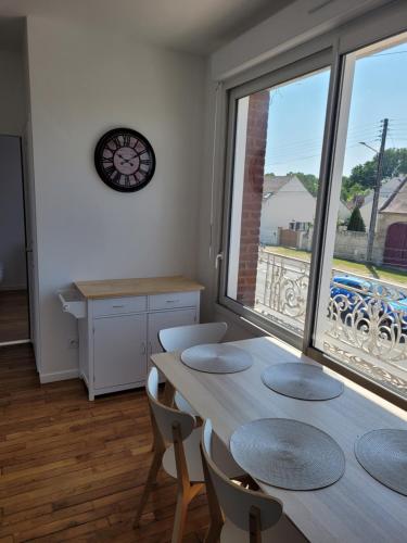 ein Esszimmer mit einem Tisch und einem großen Fenster in der Unterkunft Appartement cosy in Saint-Martin-Longueau